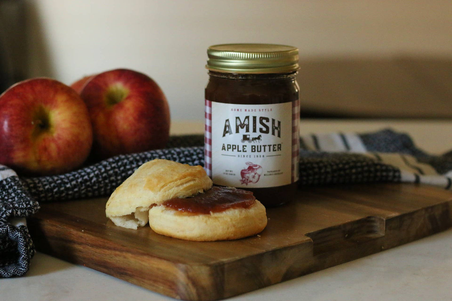 Amish Apple Butter jar with biscuits and apples on a wooden board