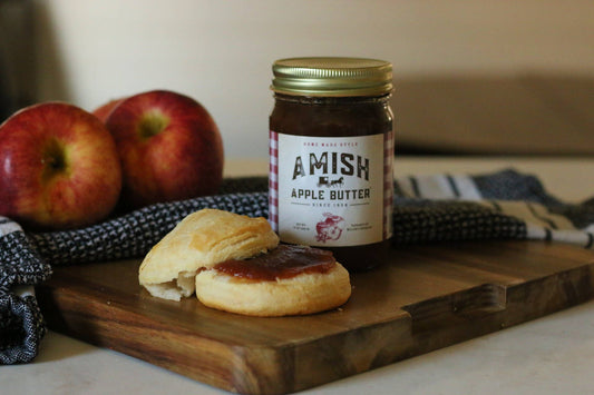 Amish Apple Butter jar with biscuits and apples on a wooden board