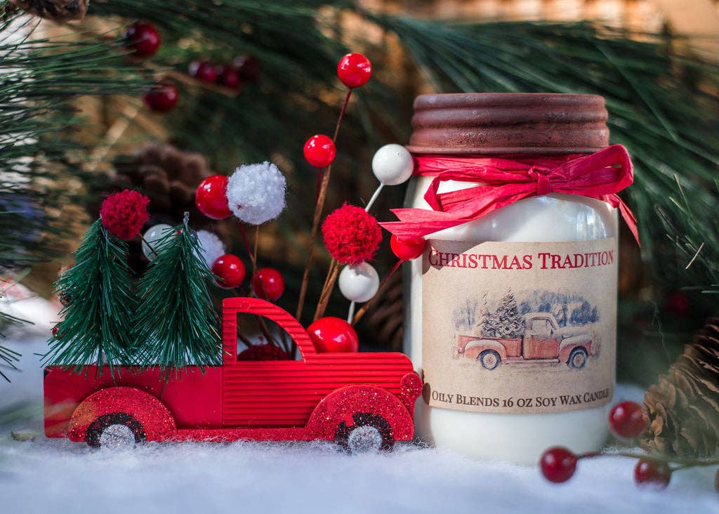 Decorative candle with a red truck and Christmas elements in front of a Christmas tree.